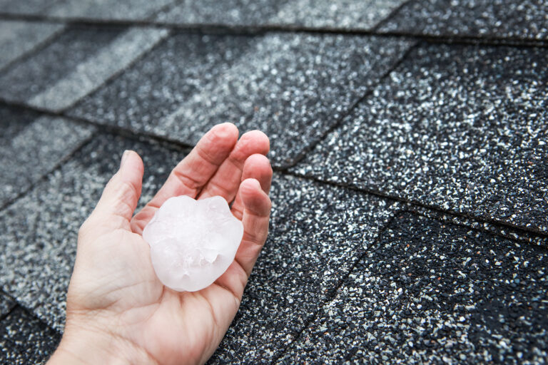 Holding a large piece of hail next to a roof