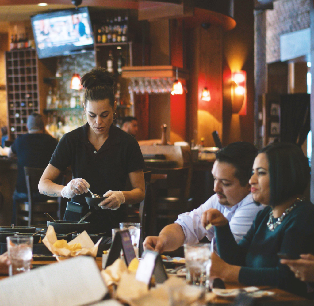 Waitress serving customers in Mexican food restaurant